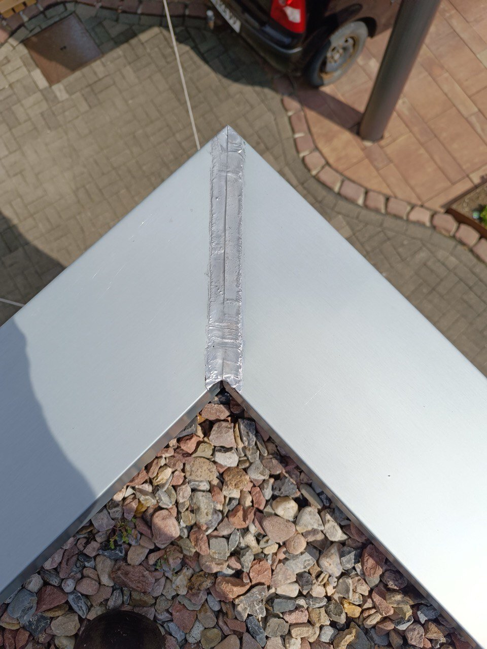 Gefalzte Aluminium-Abdeckung an der Ecke eines flachen Daches im Kiesbett